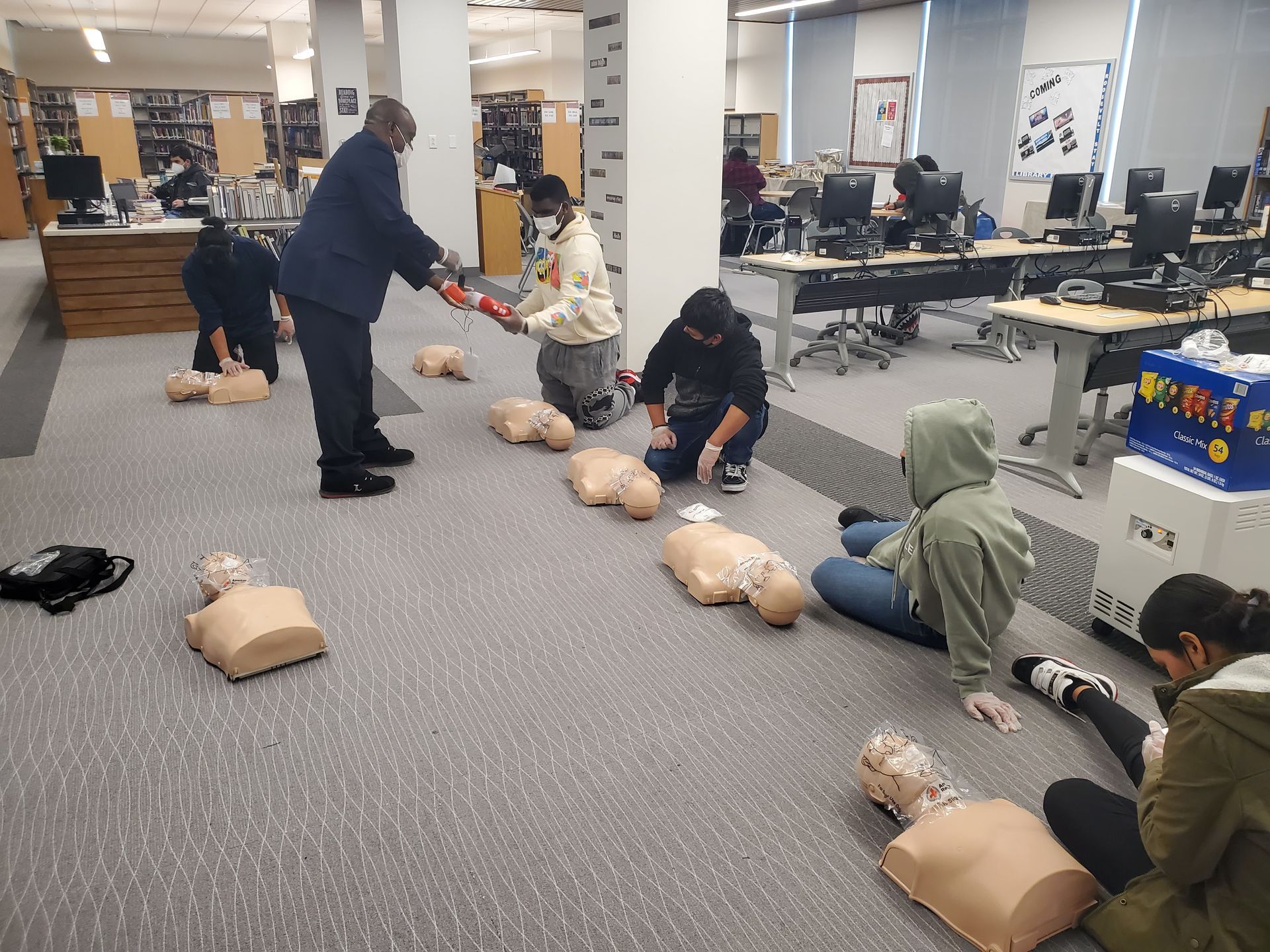 A group of people are practicing first aid in a library.
