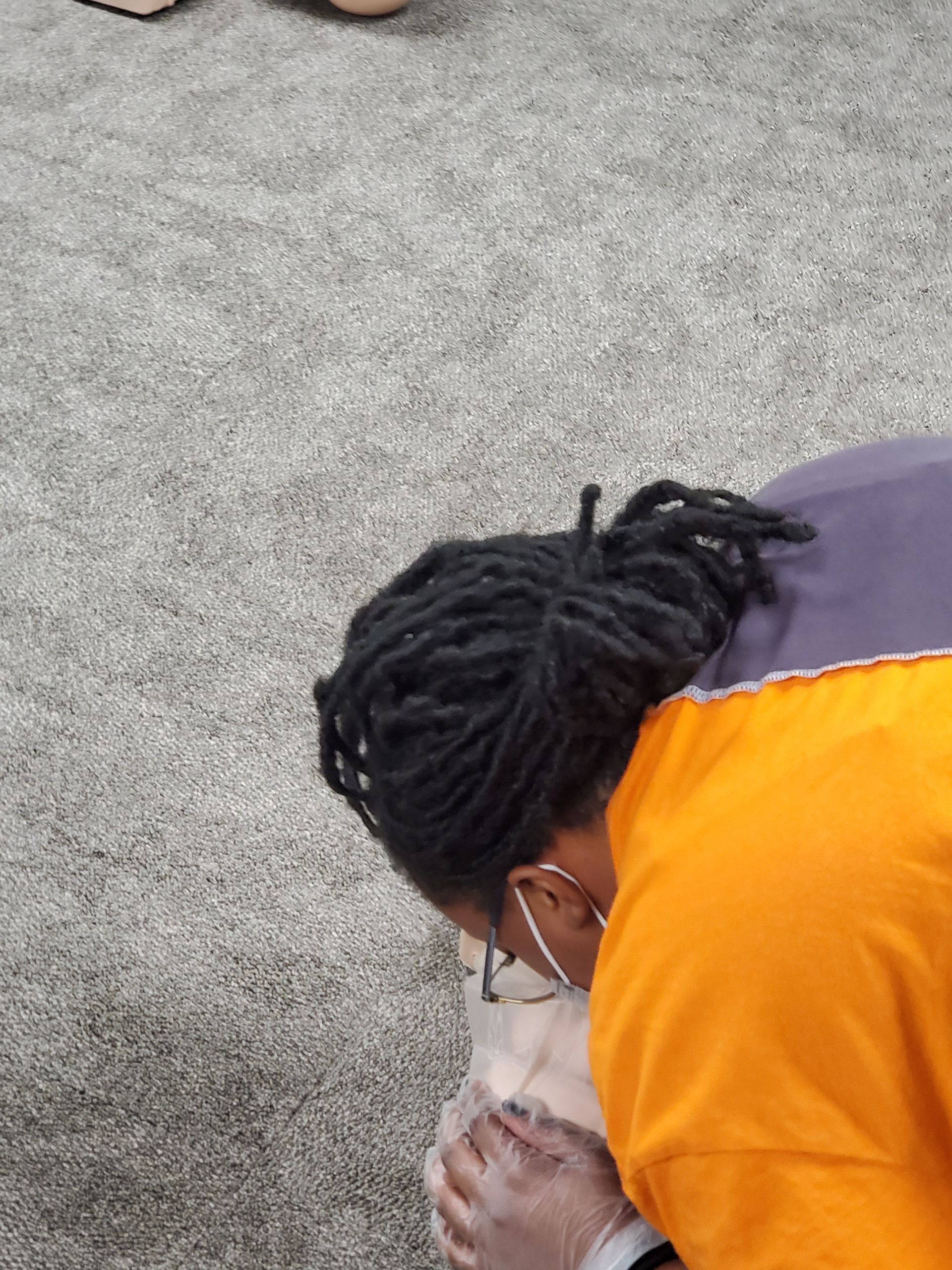 A person wearing a mask is kneeling down on the ground