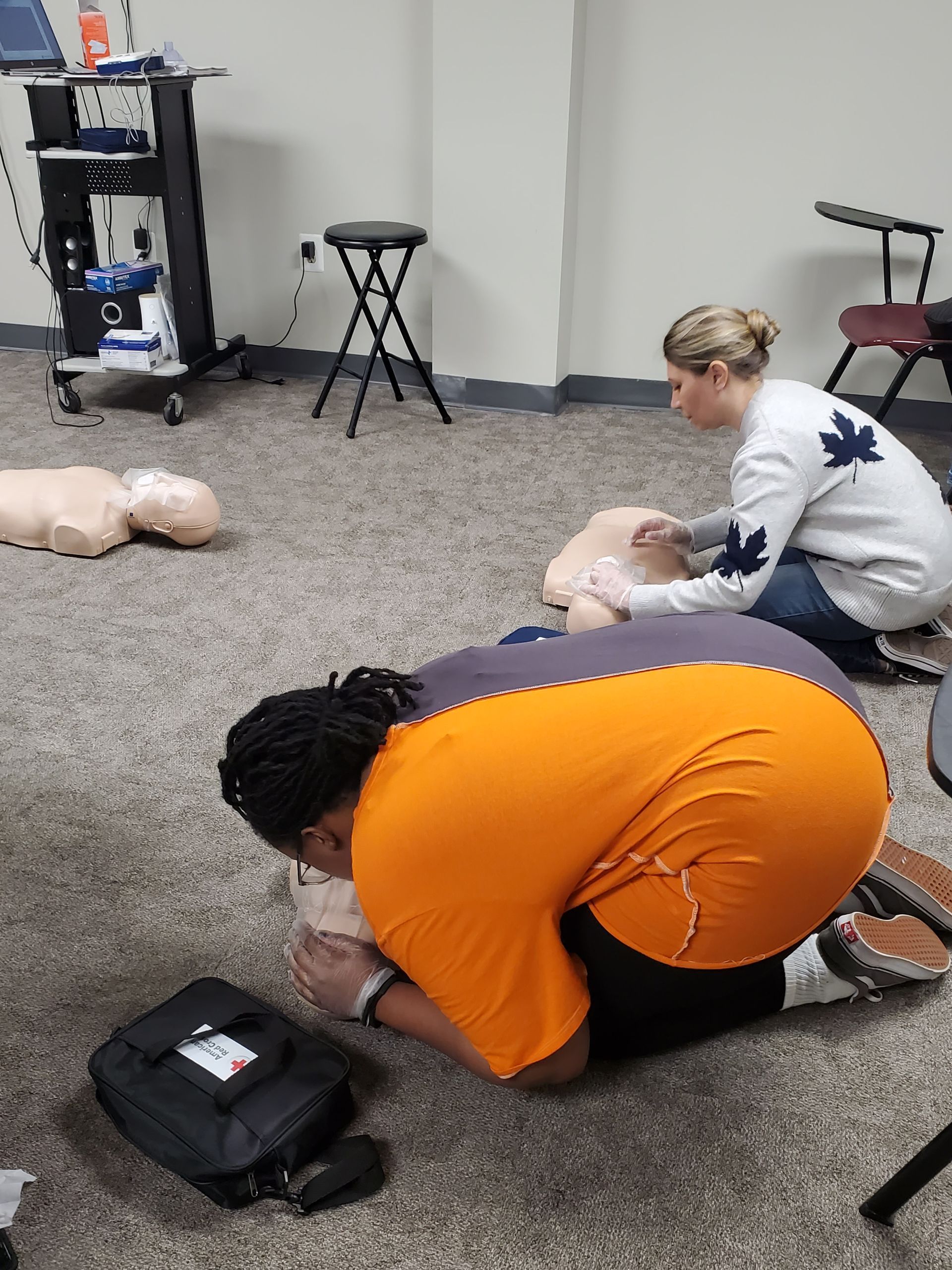 A group of people are kneeling down in a room with a mannequin.