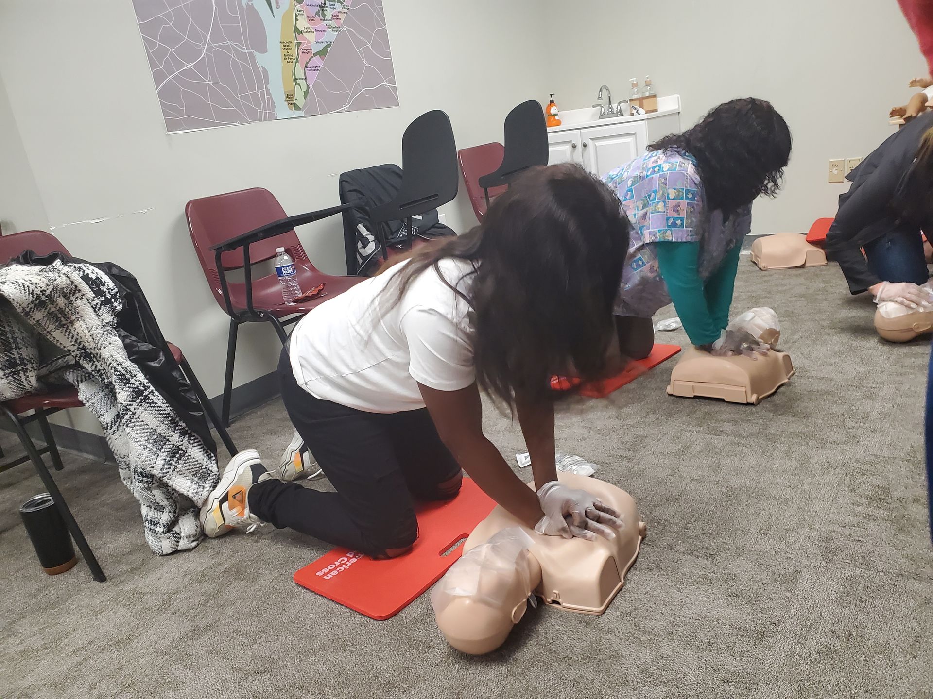 A woman is doing a cpr on a mannequin in a room.