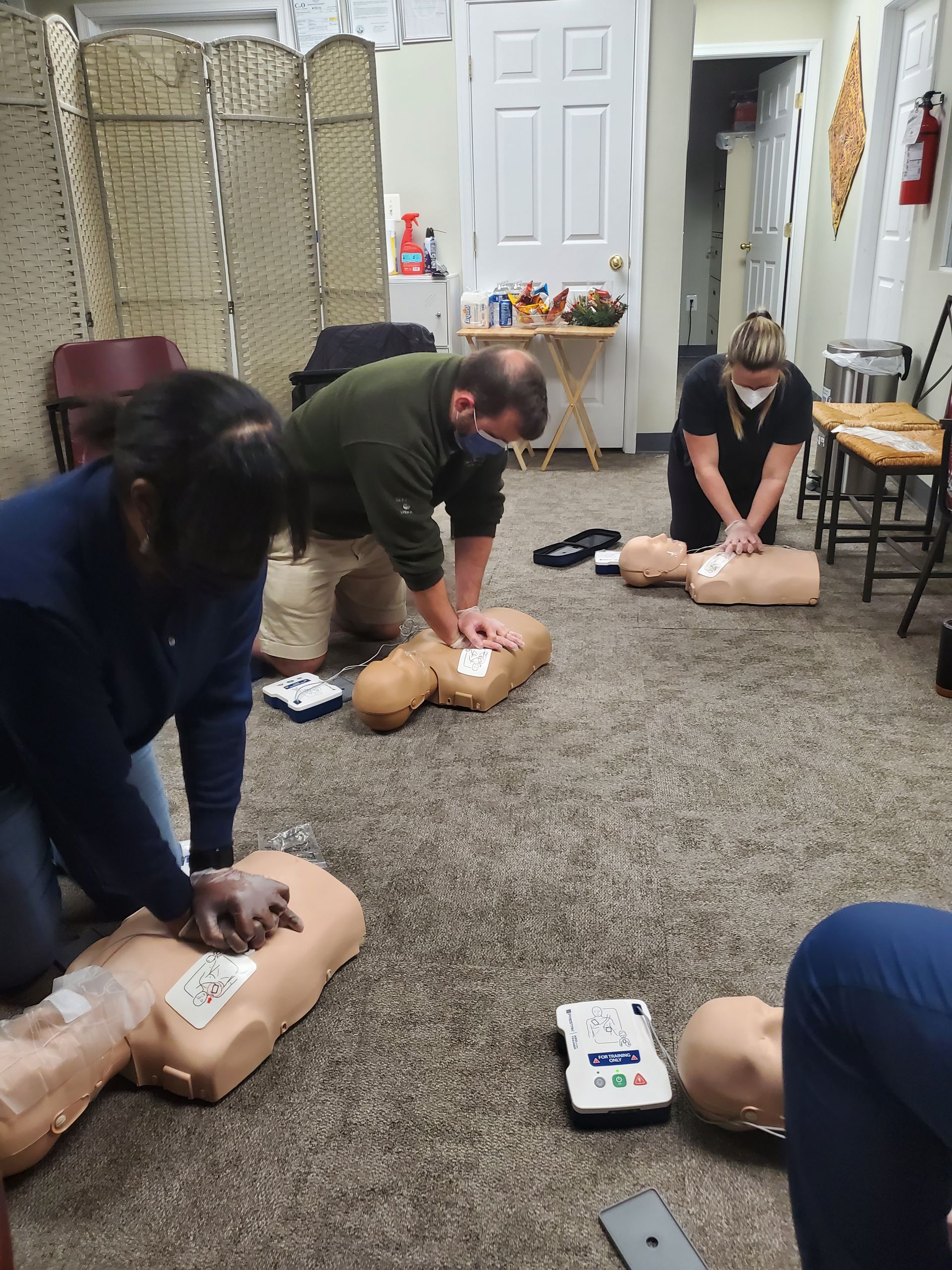 A group of people are practicing a cpr on a mannequin.