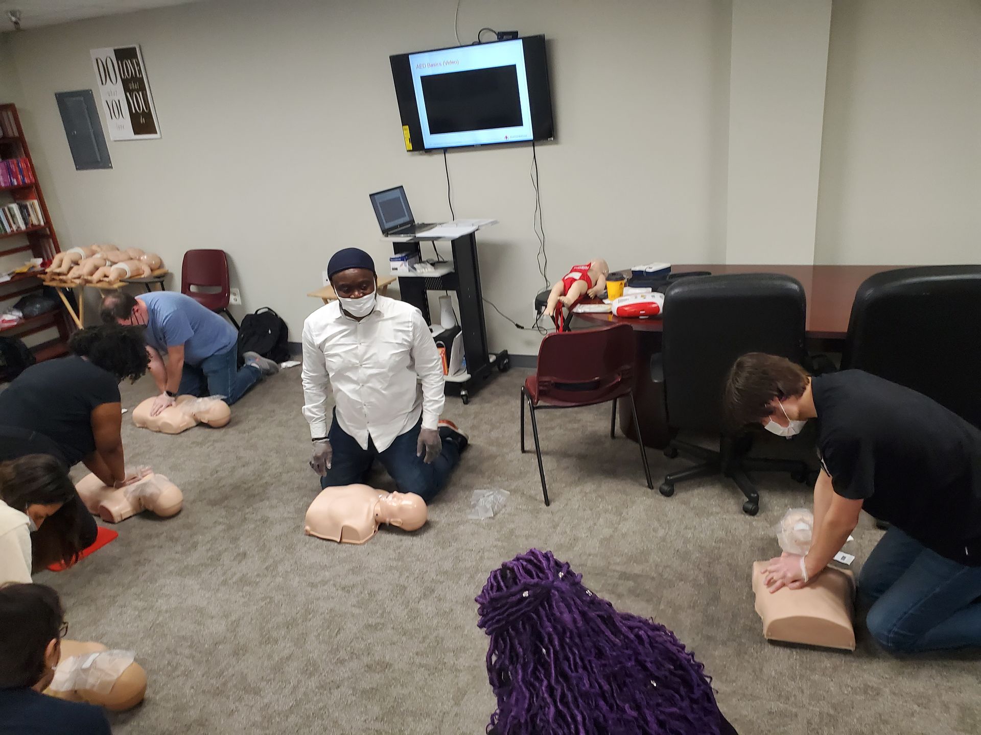 A group of people are practicing first aid in a room.