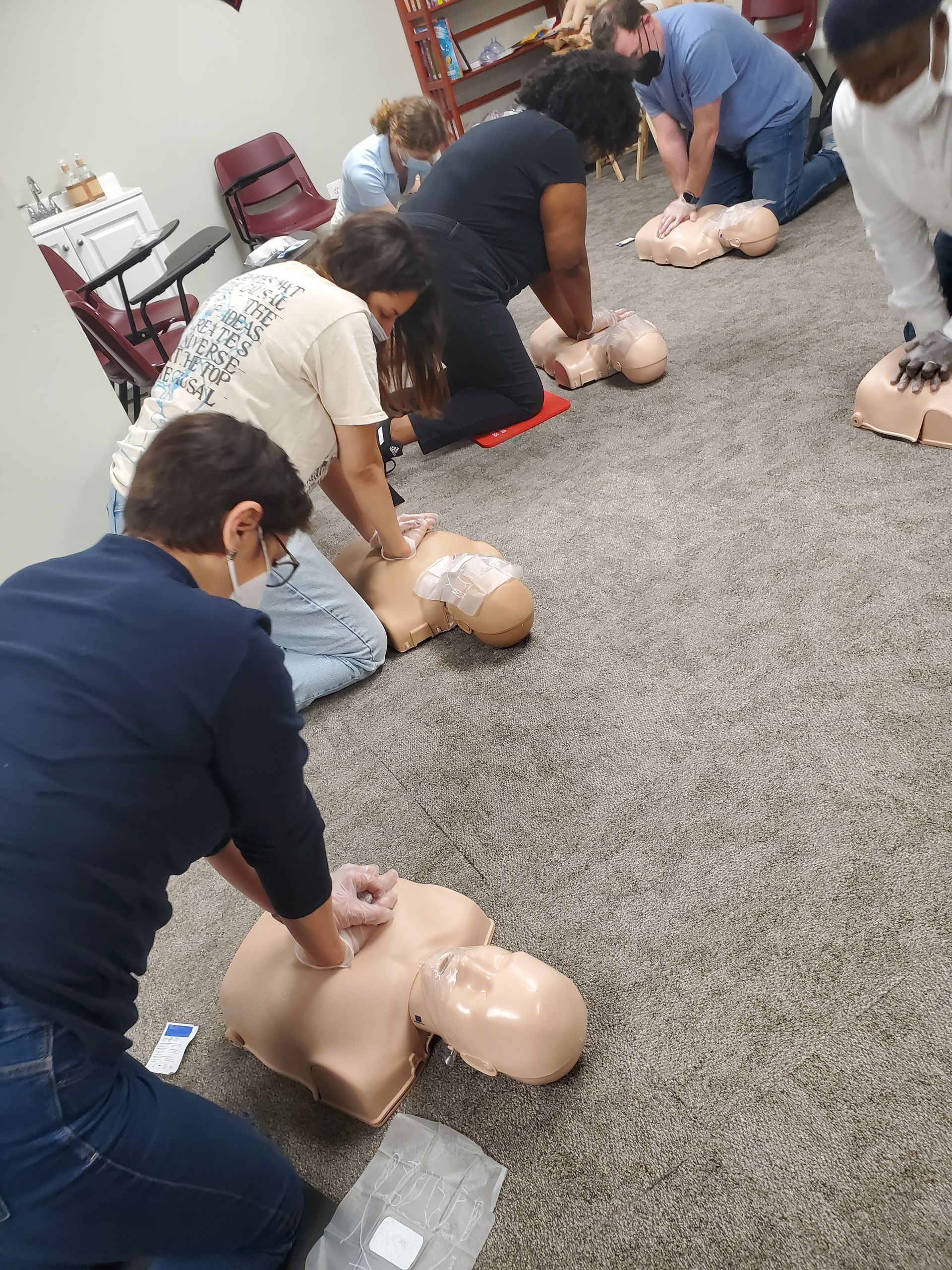 A group of people are practicing first aid on a mannequin.