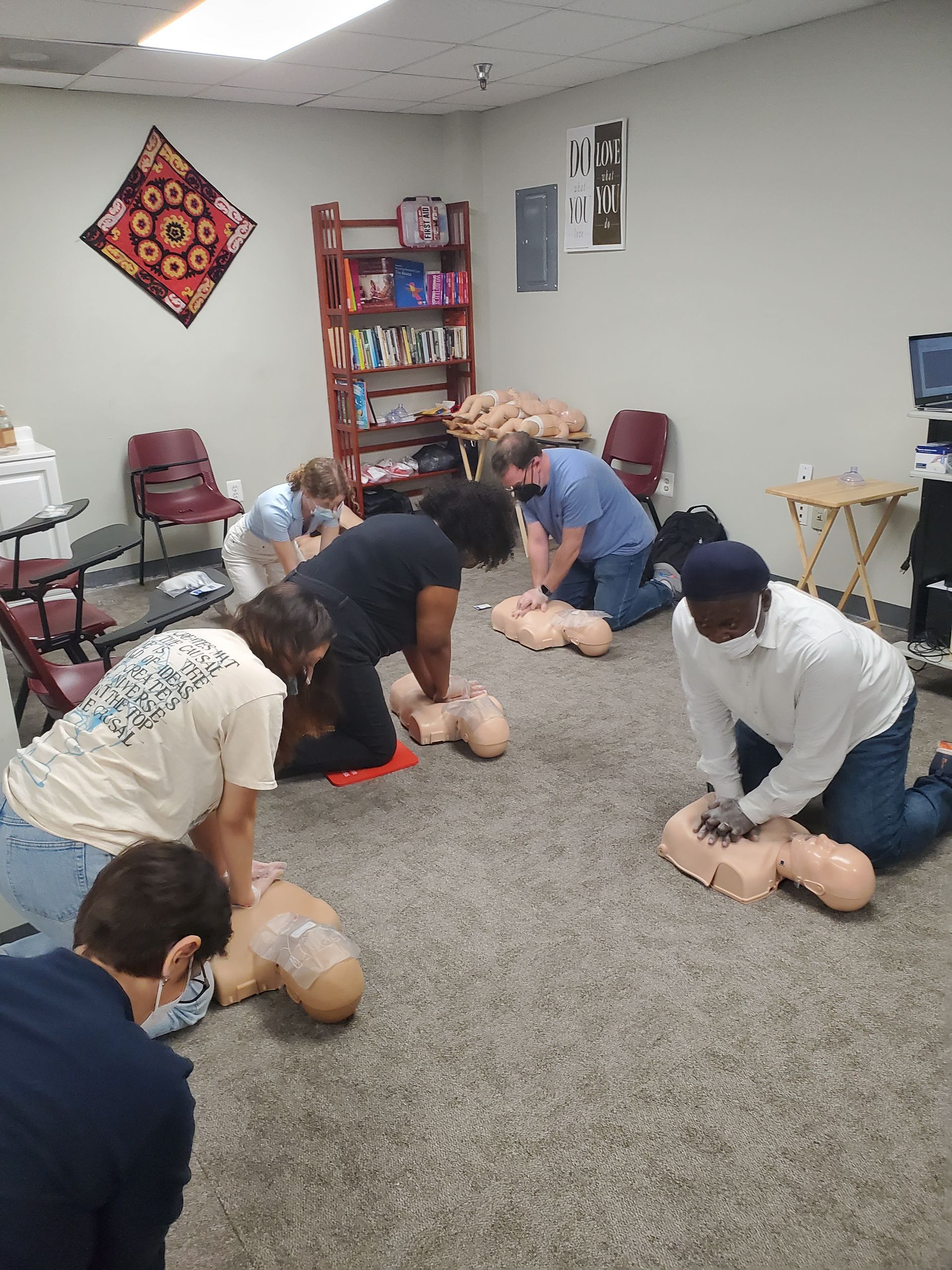 A group of people are doing a cpr on a mannequin in a room.