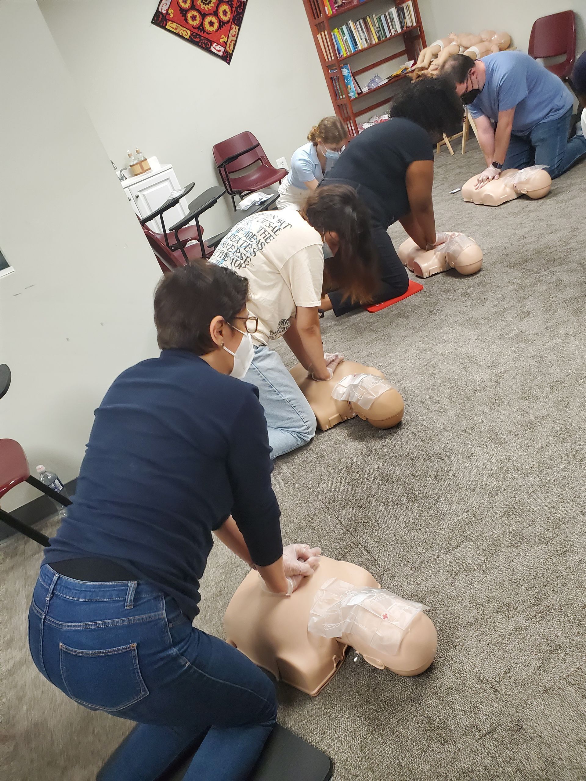 A group of people are practicing a cpr on a mannequin.
