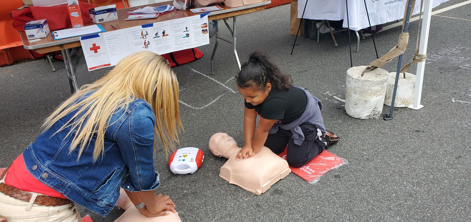 A woman and a little girl are practicing a first aid on a mannequin.