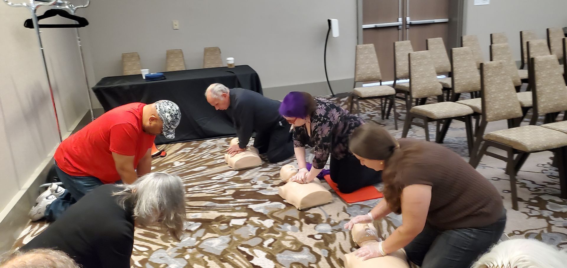 A group of people are kneeling on the floor doing a heart massage.