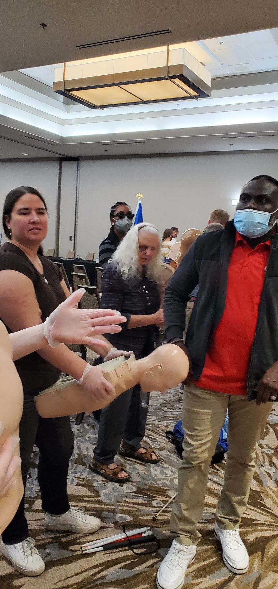 A group of people are standing around a mannequin in a room.