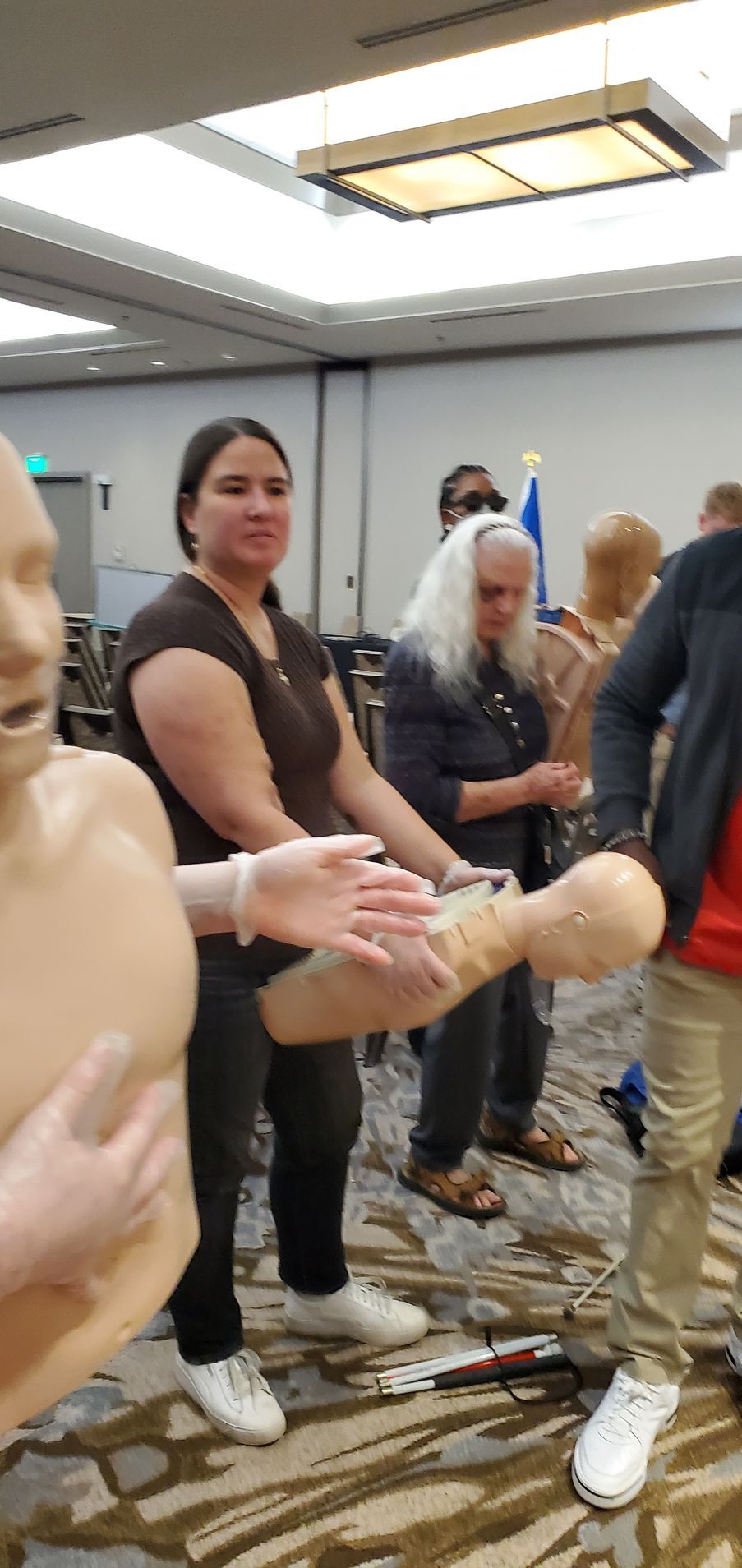 A group of people are standing around a mannequin in a room.