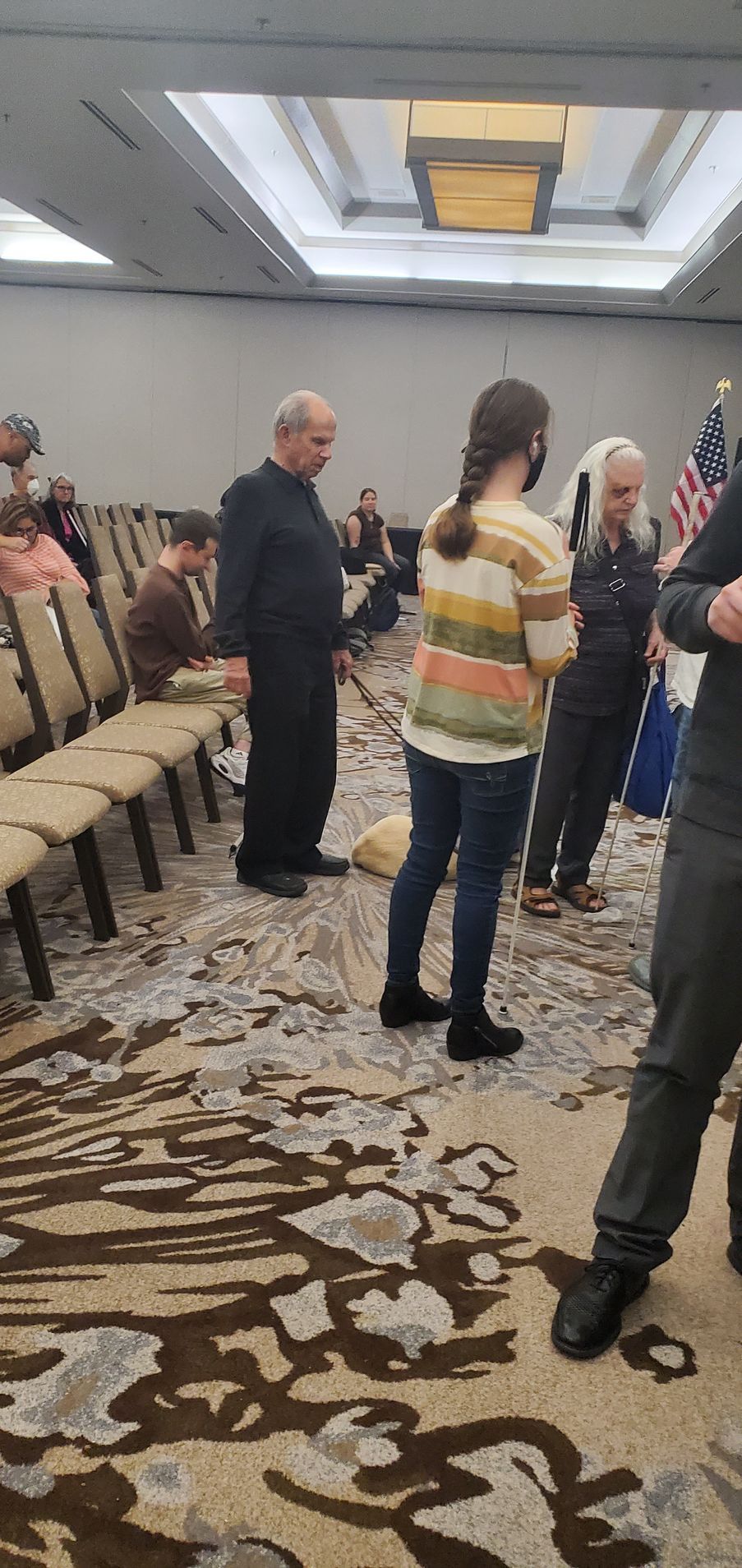 A group of people are standing in a room with chairs.
