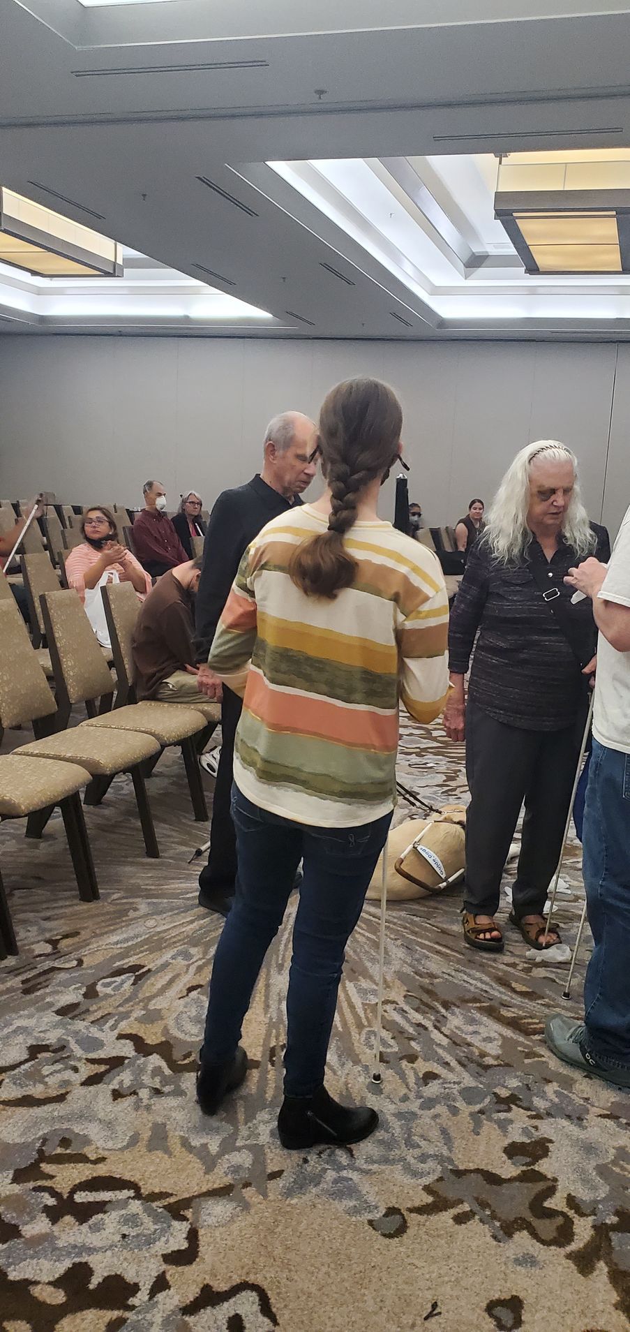 A group of people are standing in a room talking to each other.