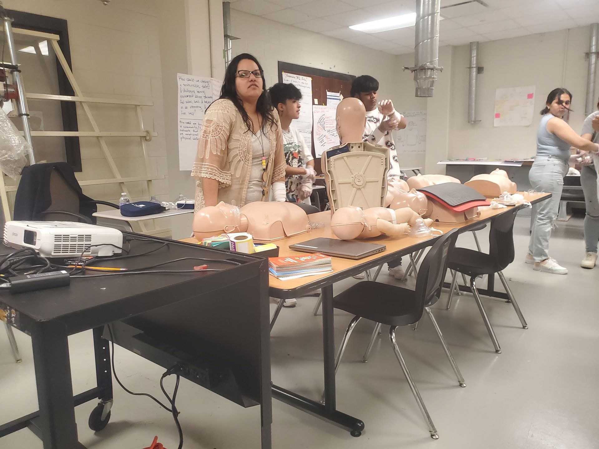 A group of people are standing around a table with mannequins on it.