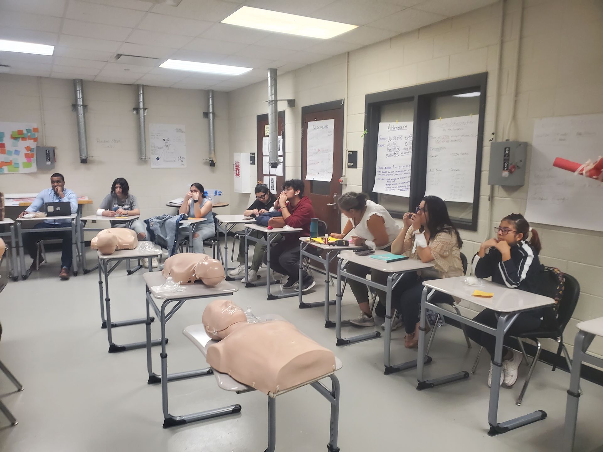 A group of people are sitting at desks in a classroom.