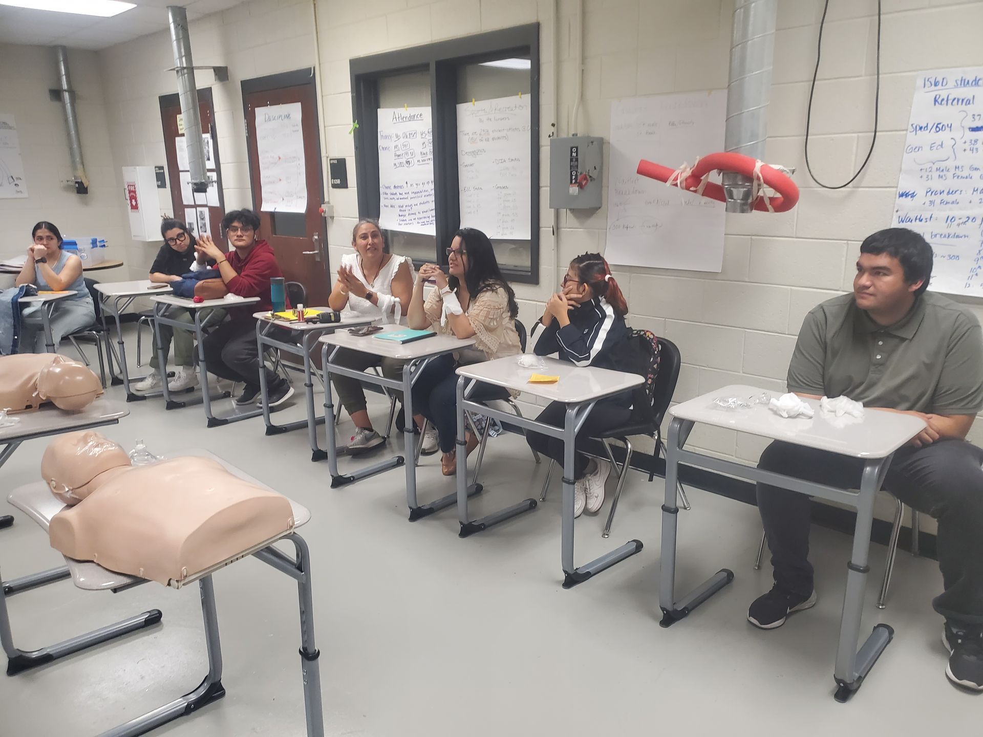 A group of people are sitting at desks in a classroom.