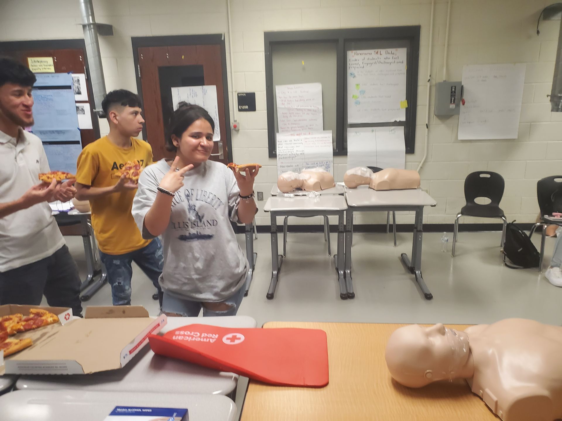 A group of people are standing around a table eating pizza.