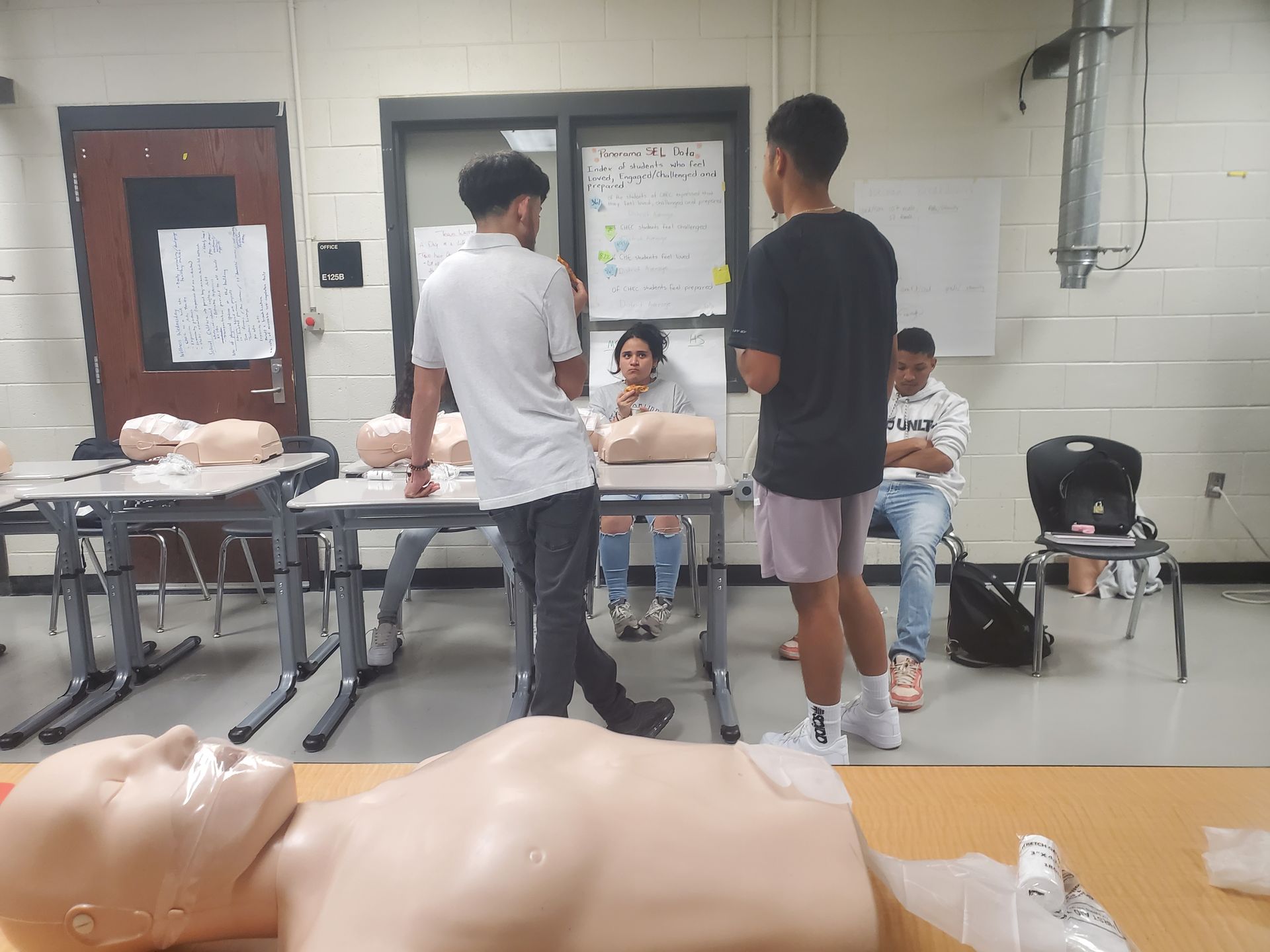 A group of young men are standing around a table with mannequins.