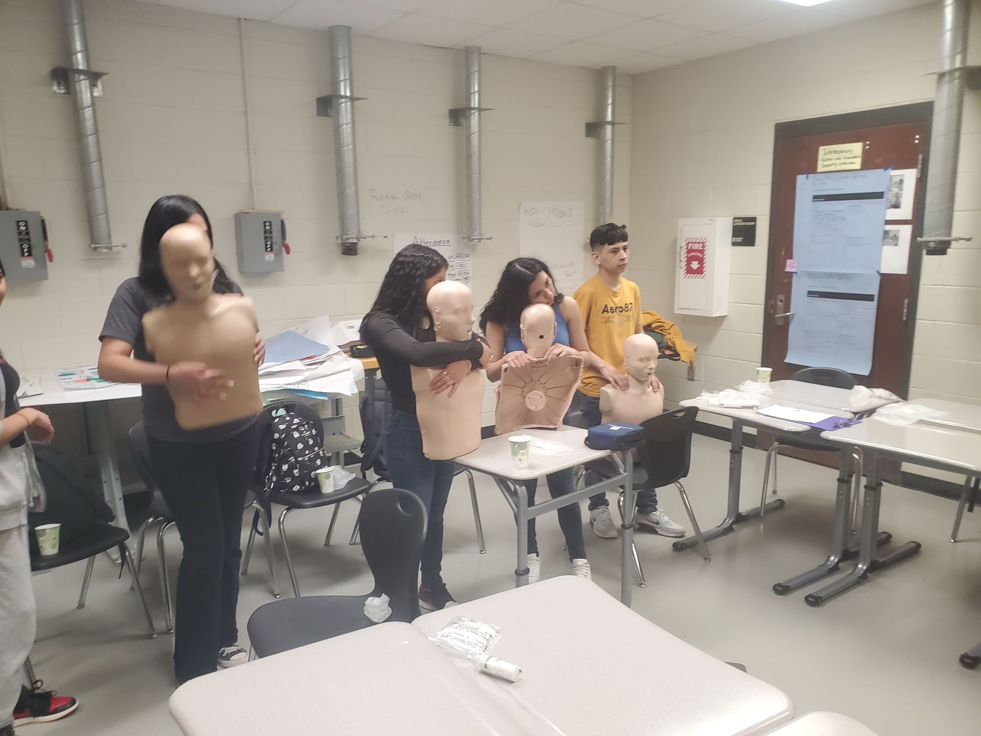 A group of people are standing around mannequins in a room.