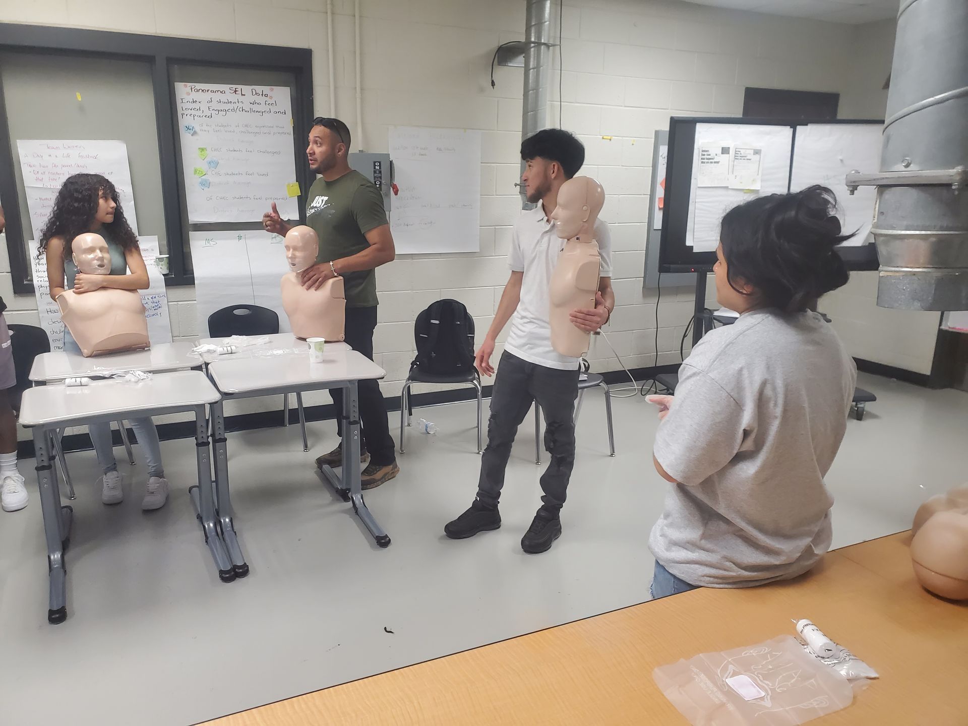 A group of people are standing around a table in a classroom.