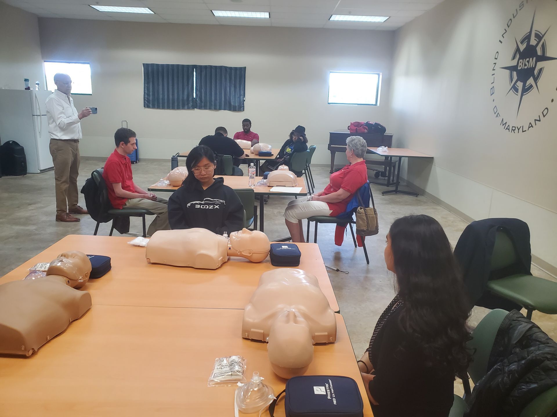 A group of people are sitting at tables in a room with mannequins on them.