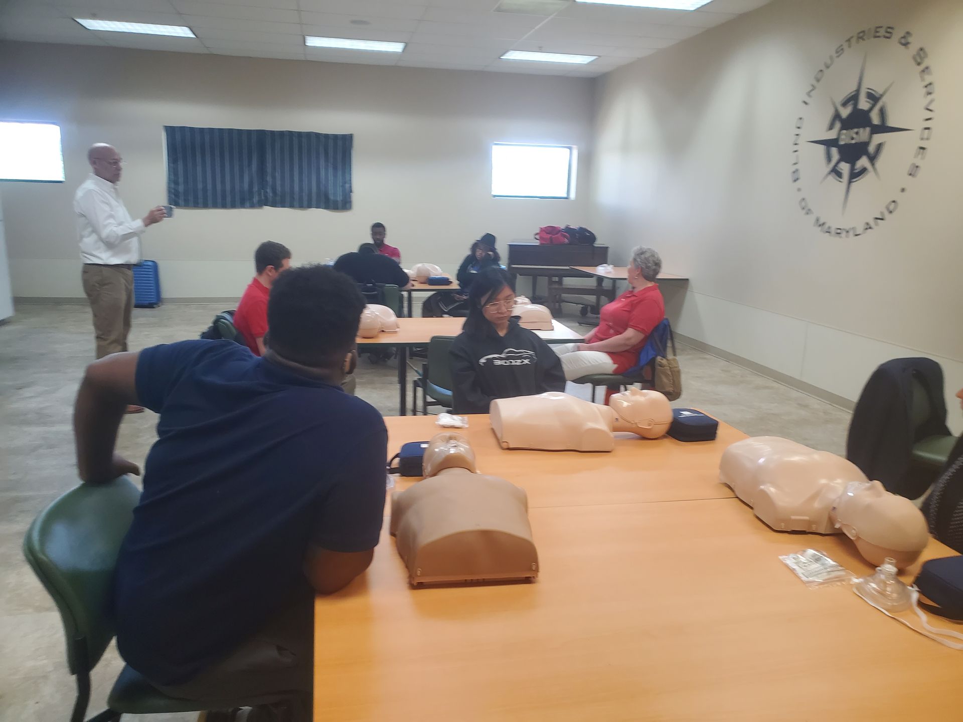 A group of people are sitting at tables in a room with mannequins.