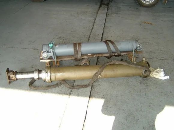 Two Hydraulic Cylinders Strapped Together on a Concrete Surface — Alloway Hydraulics in Mount Saint John, QLD