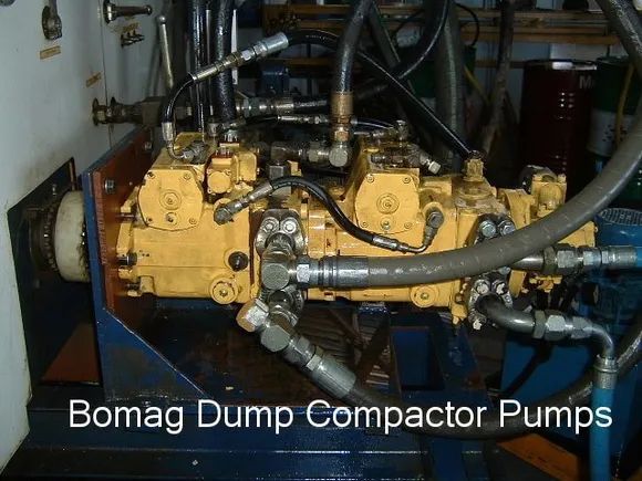 Yellow Bomag Dump Compactor Pumps With Black Hoses and Fittings on a Blue Metal Frame — Alloway Hydraulics in Mount Saint John, QLD