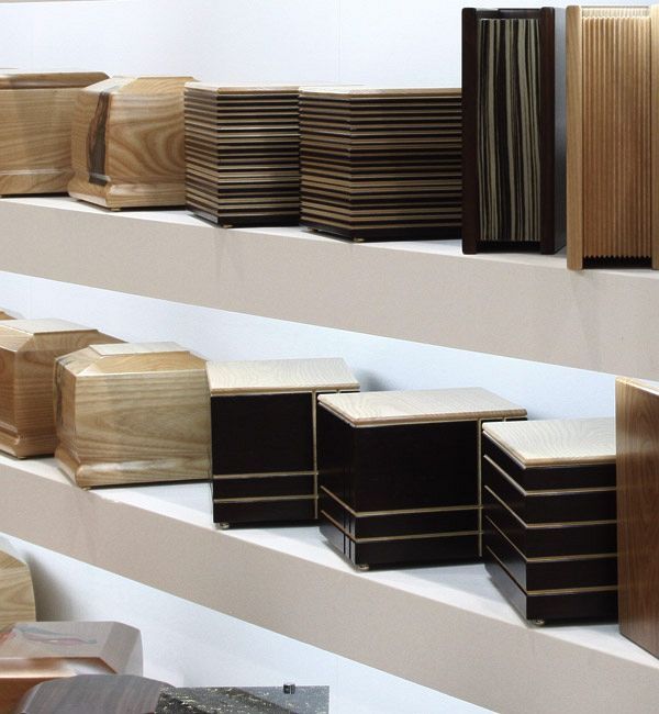 Una mostra di urne di legno su uno scaffale bianco