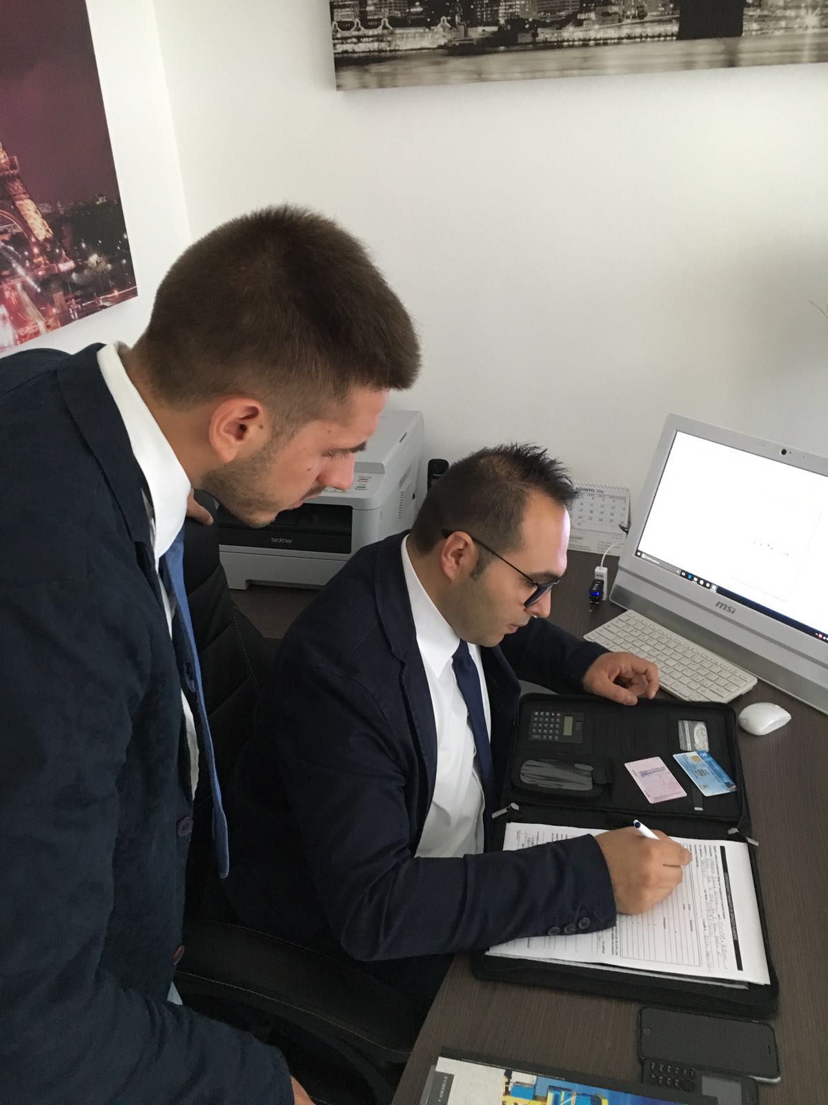 Due uomini in giacca e cravatta guardano lo schermo di un computer.