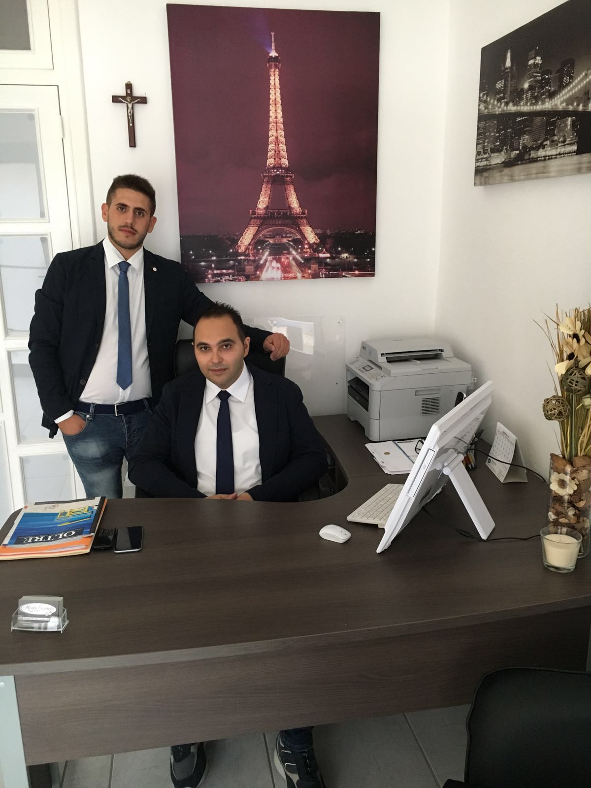 Due uomini in piedi uno accanto all'altro davanti a un'immagine della Torre Eiffel