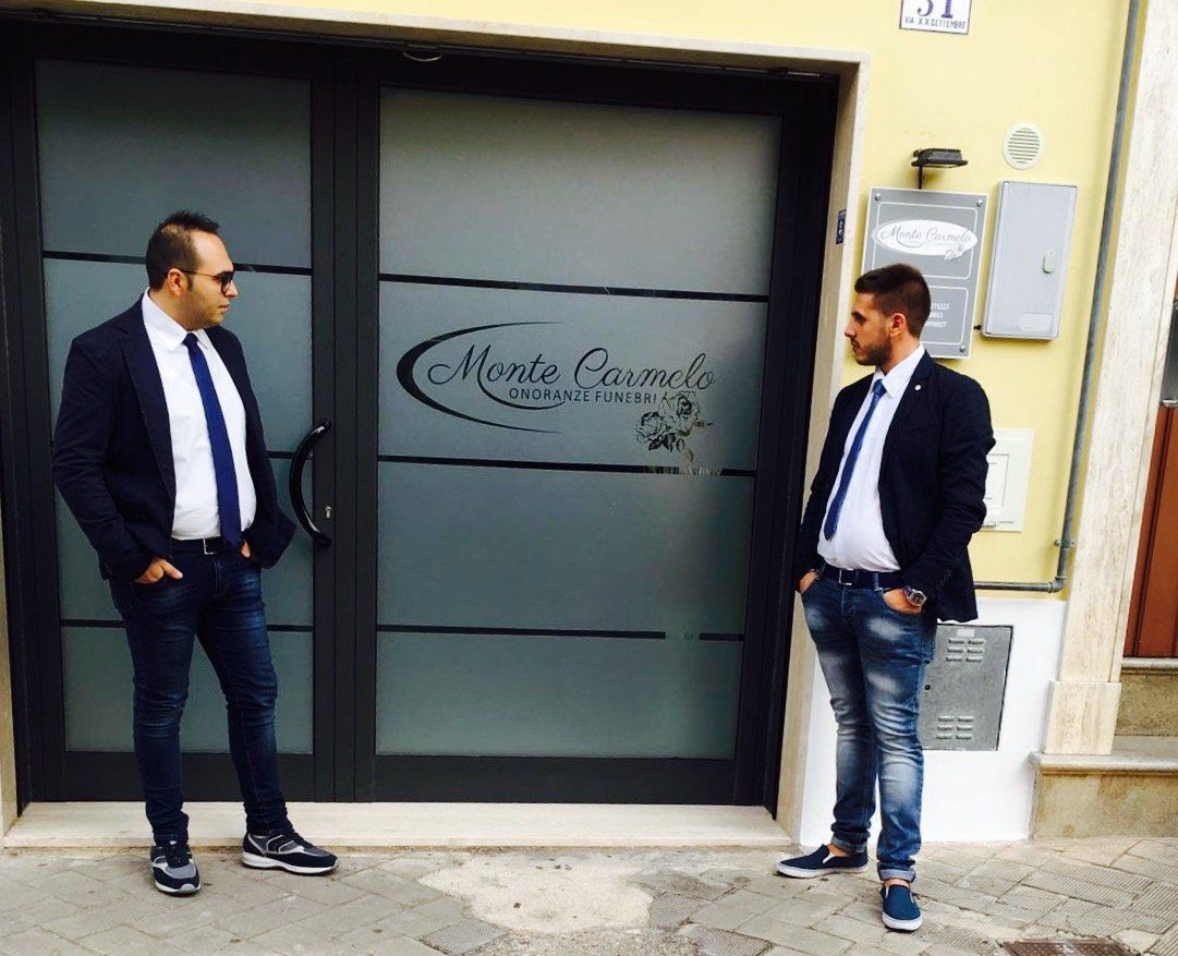 Due uomini sono in piedi davanti a un edificio con la scritta monte cappuccio