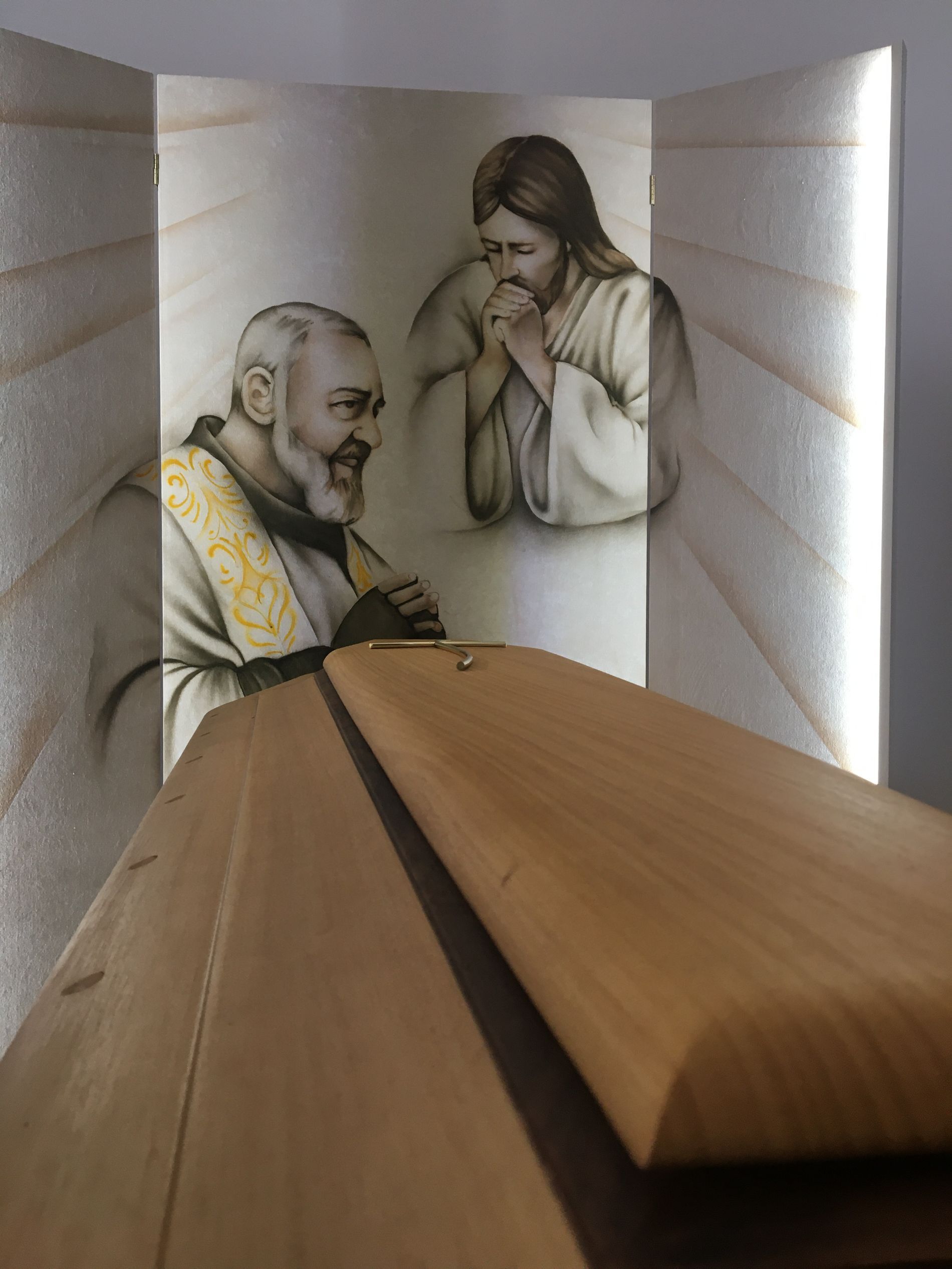 Una bara di legno con sopra un dipinto di Gesù e Padre Pio.