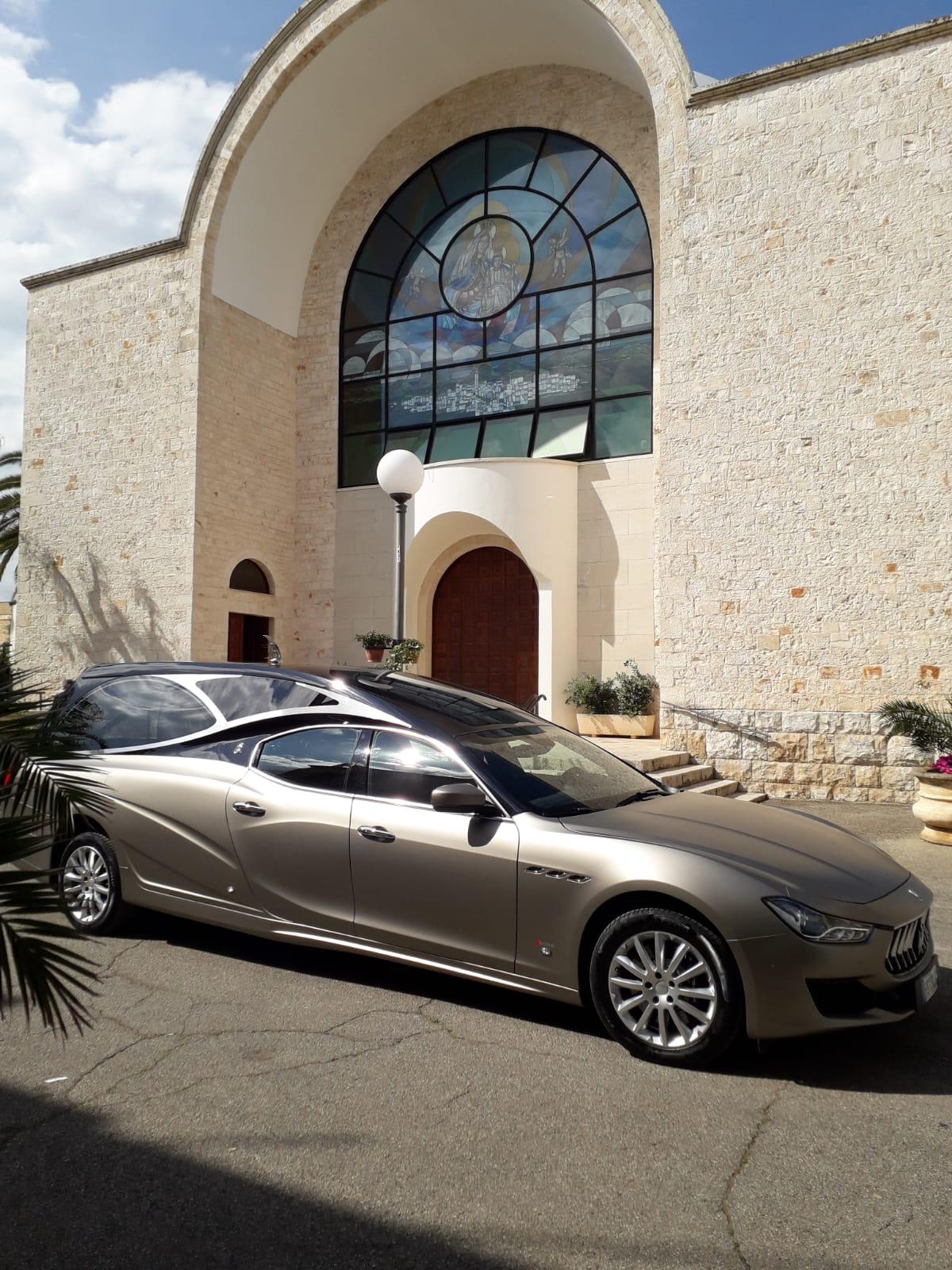 Un'auto è parcheggiata davanti a un edificio con una vetrata.