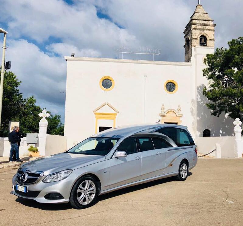 Un'auto argentata è parcheggiata davanti a un edificio bianco.