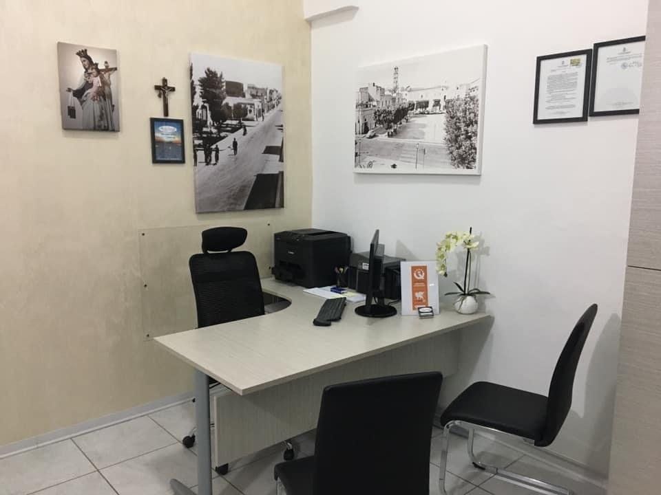Un piccolo ufficio con una scrivania, sedie e quadri sul muro