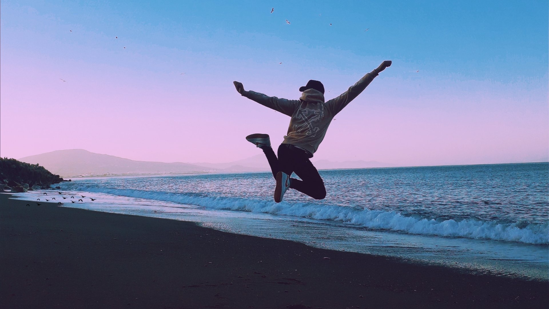 Person jumping in air near ocean
