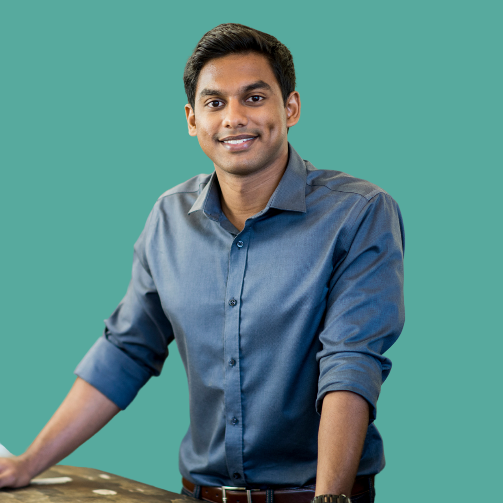 A man in a blue shirt is standing in front of a blue background