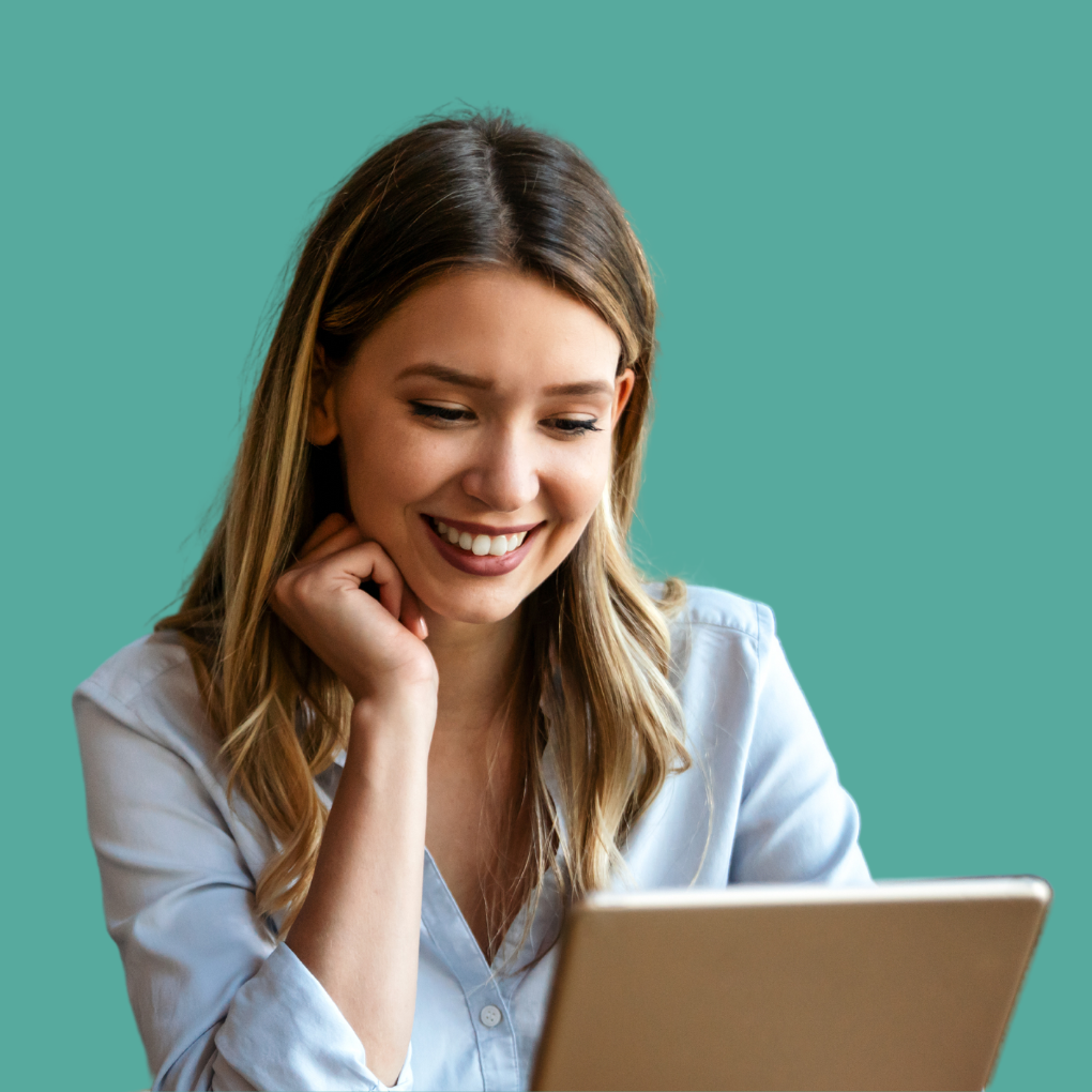 A woman is smiling while looking at a laptop computer.