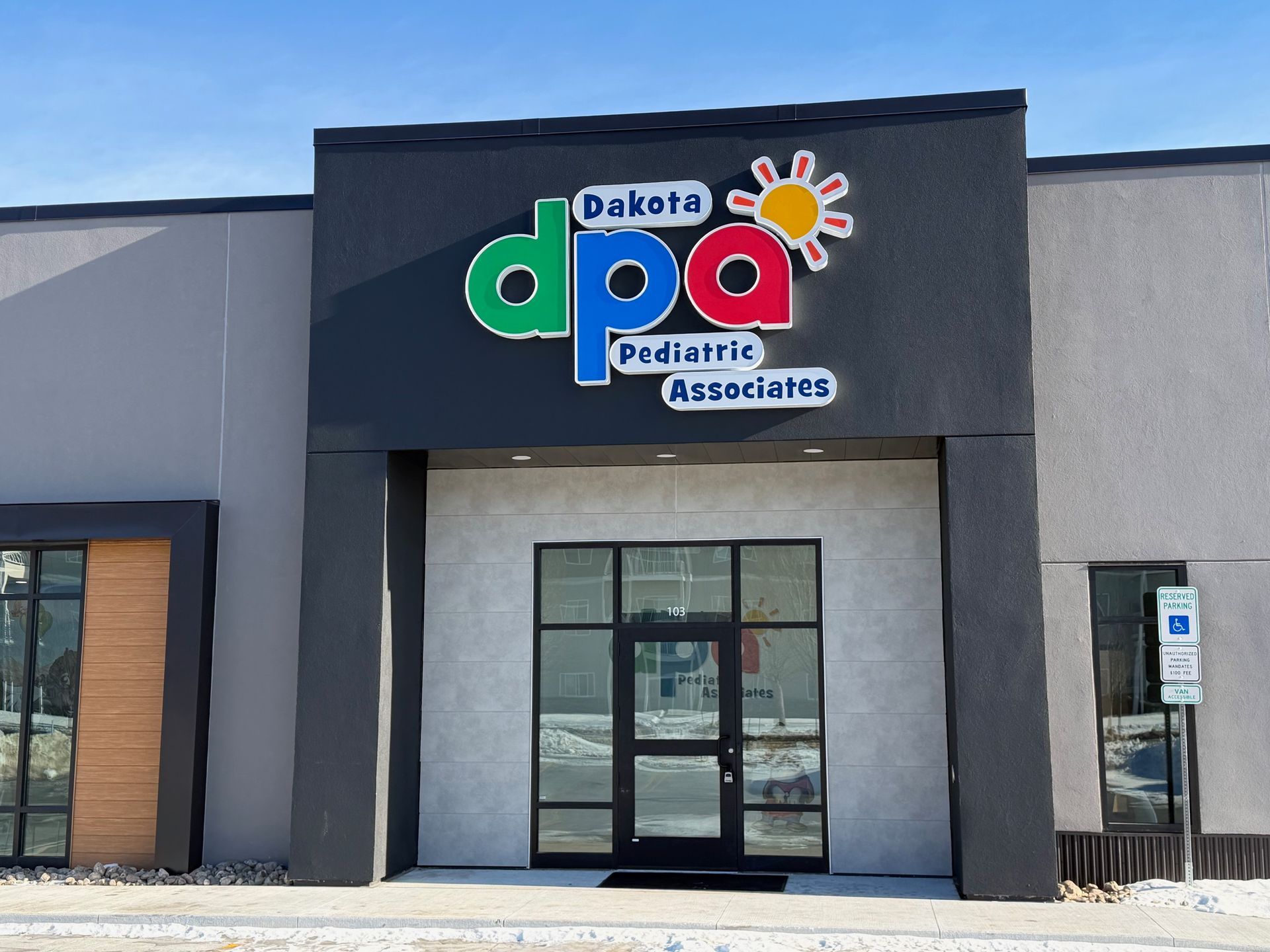 Outside of Dakota Pediatric Associates with the name on the one-story building and blue sky in the background.