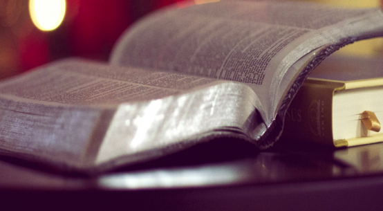 Open Bible on a table, with pages reflecting light.