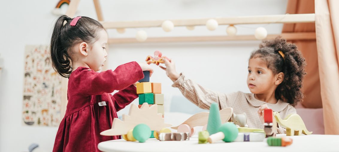 Two children playing with wooden blocks and toys at a table.