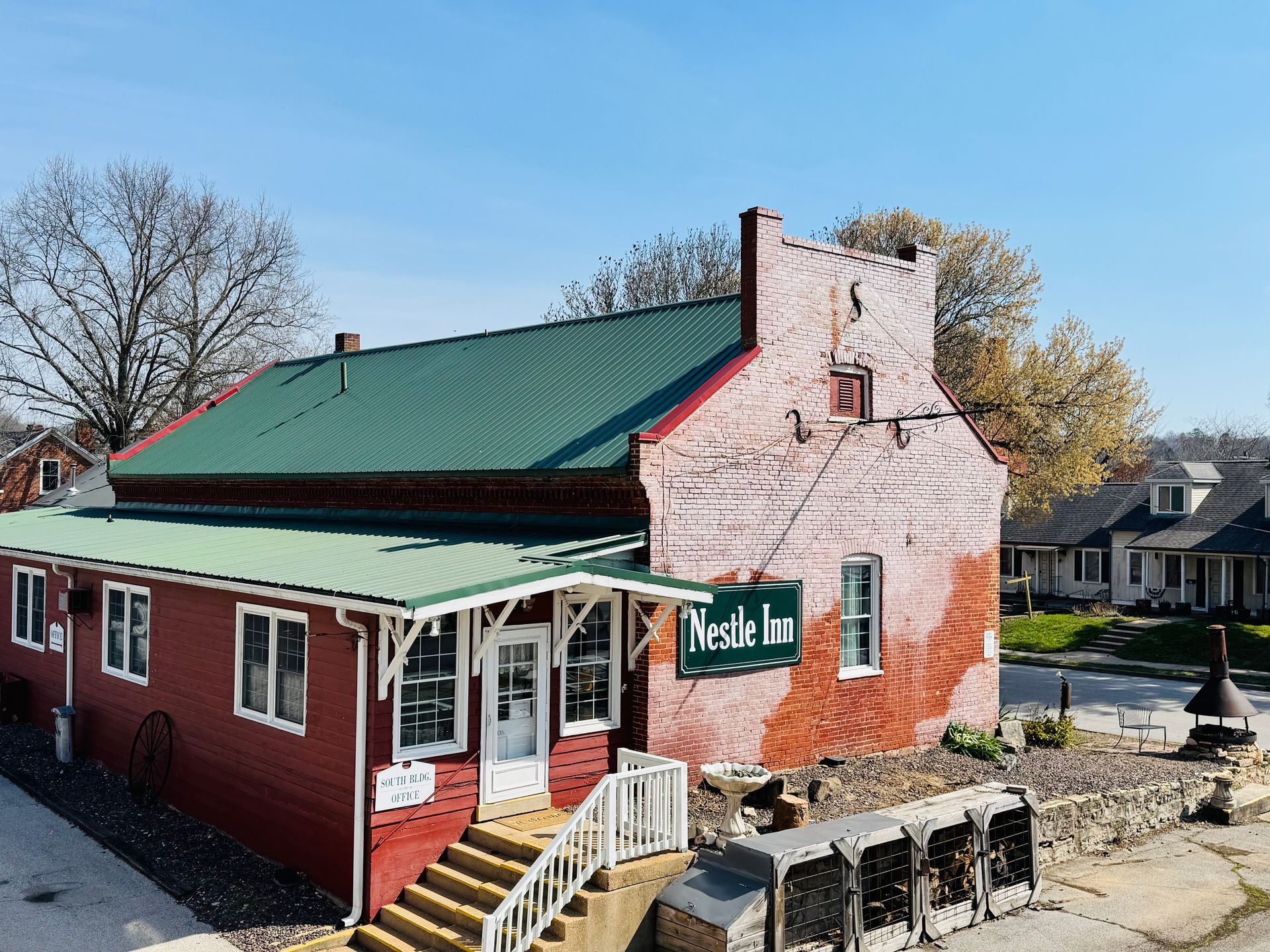 A red brick building with a green metal roof and a sign reading