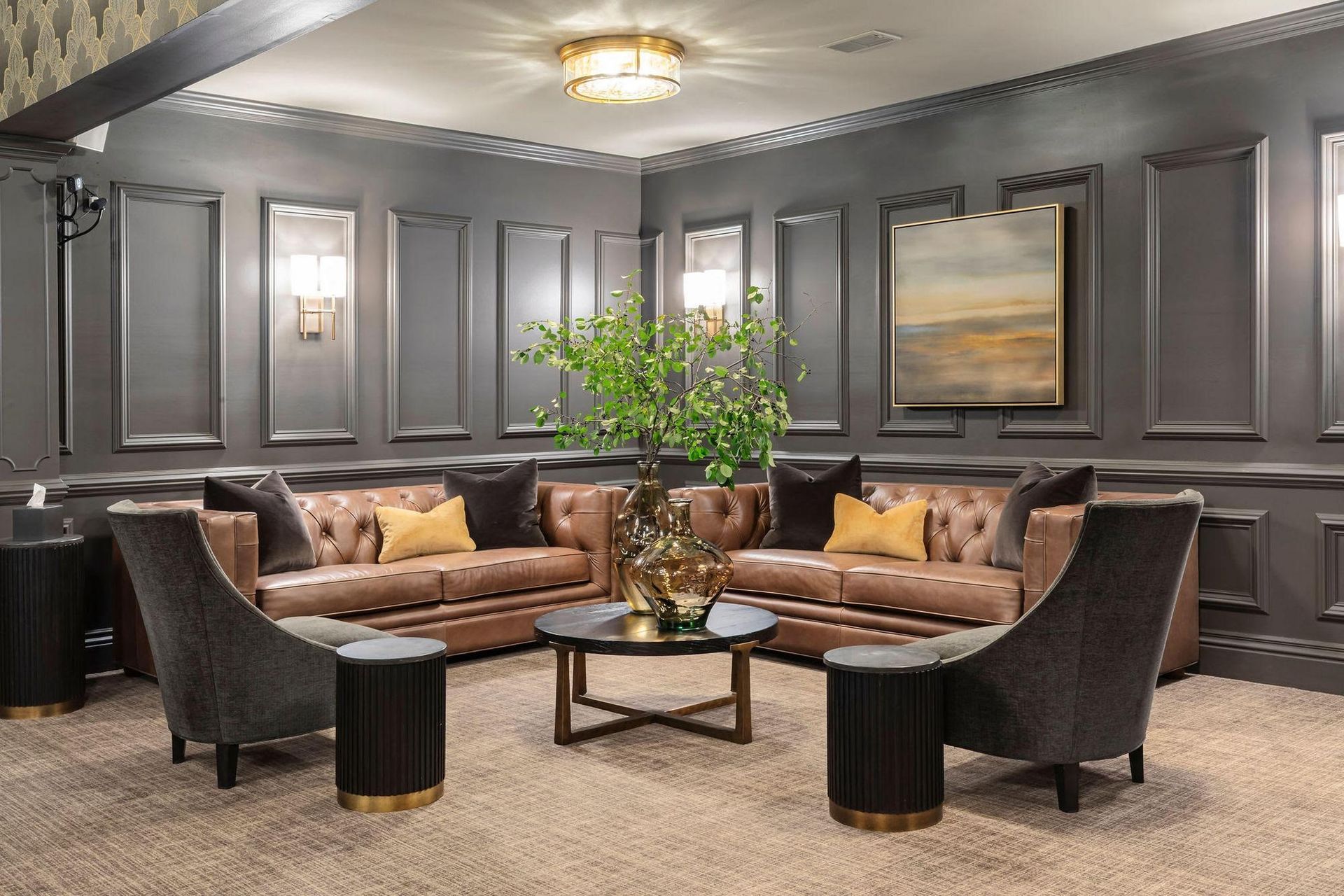 Elegant gray lounge with brown velvet sofas, black chairs, glass coffee table, and a large potted plant