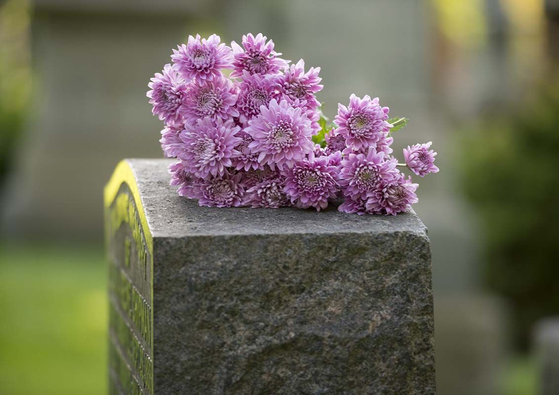 Pink flowers resting on a gray gravestone in a cemetery