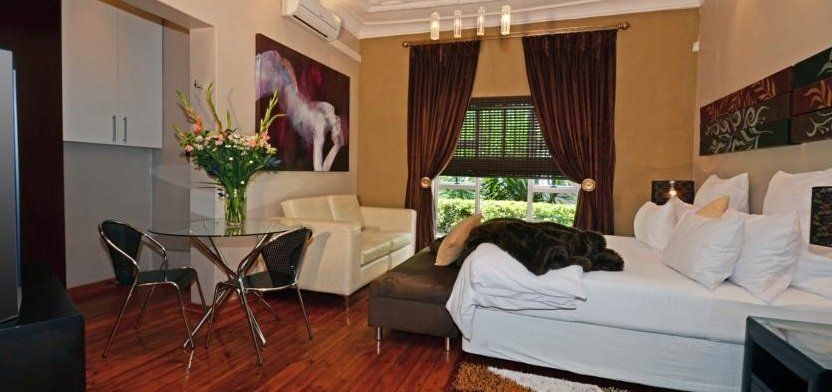 Modern bedroom with white furniture, large bed, and a seating area with a view.