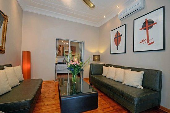 Modern living room with leather sofas, wooden floor, and abstract wall art.