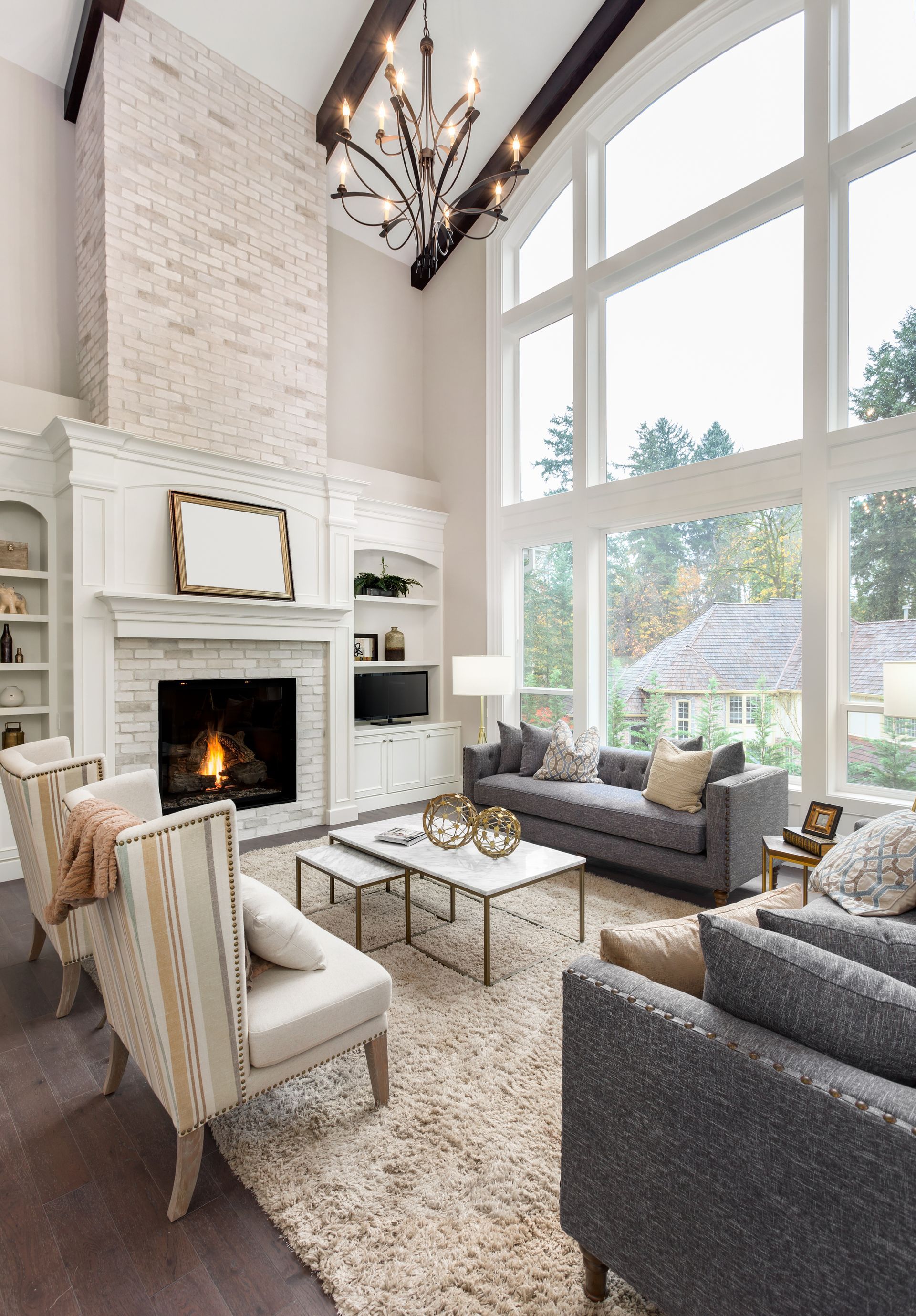 Elegant living room with fireplace, high windows, two sofas, and armchairs; neutral colors.