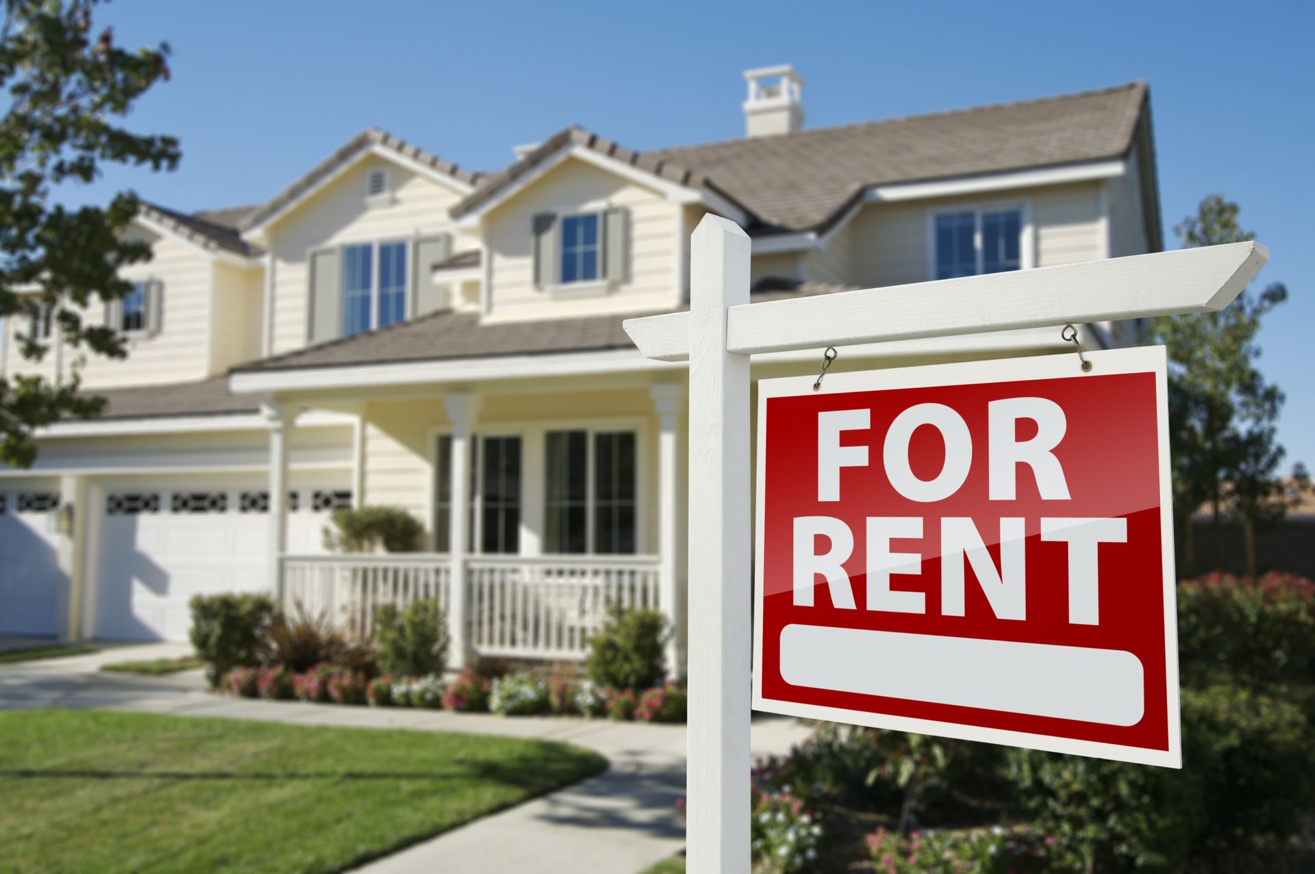 House for rent; sign in front of a two-story beige house with green lawn.