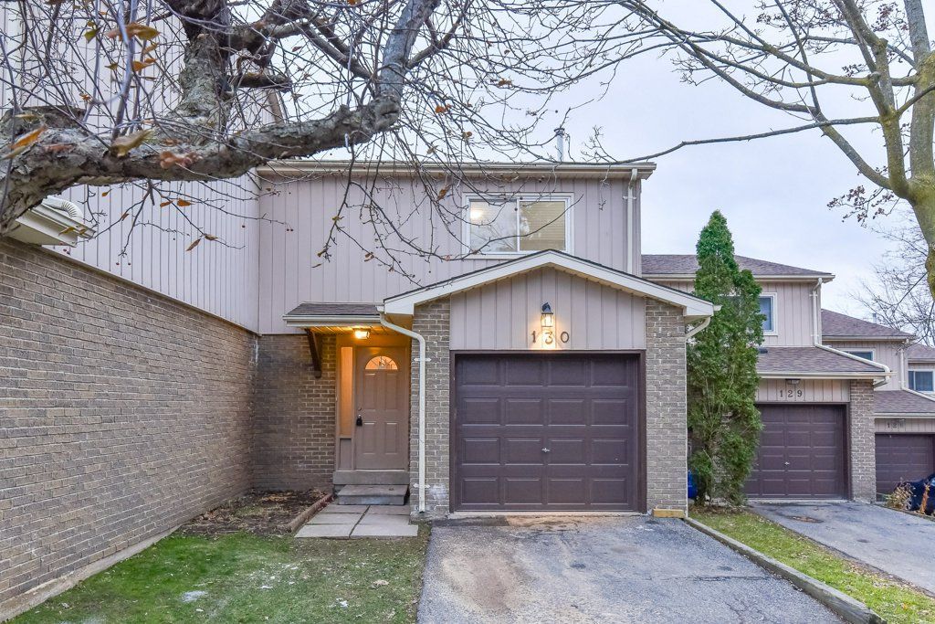 Townhouse exterior with brown garage door, brick facade, and small front yard with dead grass.