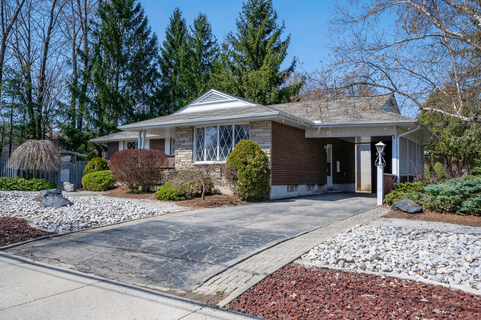 House exterior, one story with a driveway, surrounded by landscaping, trees in the background.