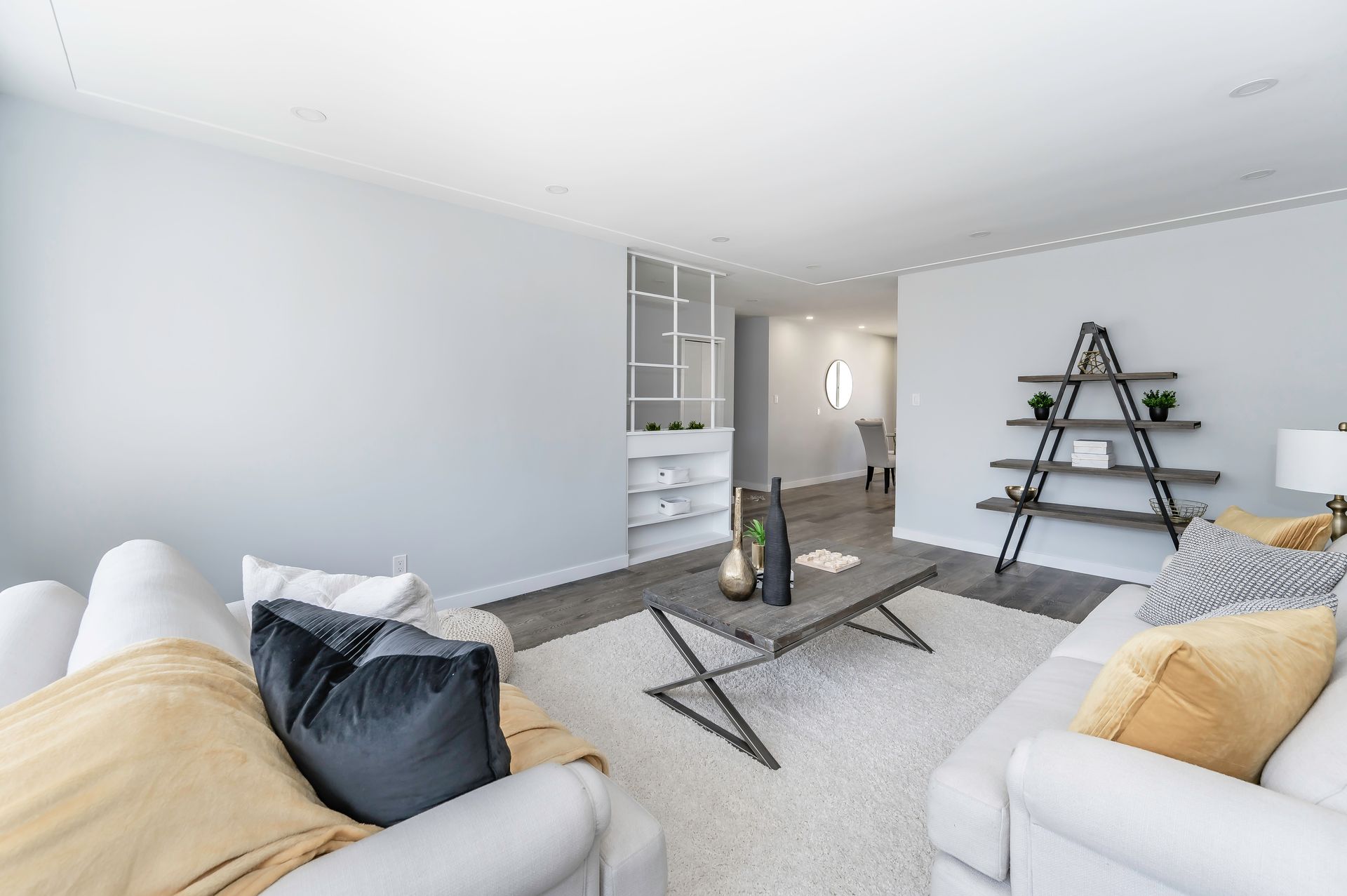 Living room with white sofa, gray coffee table, and open shelving, featuring neutral tones.